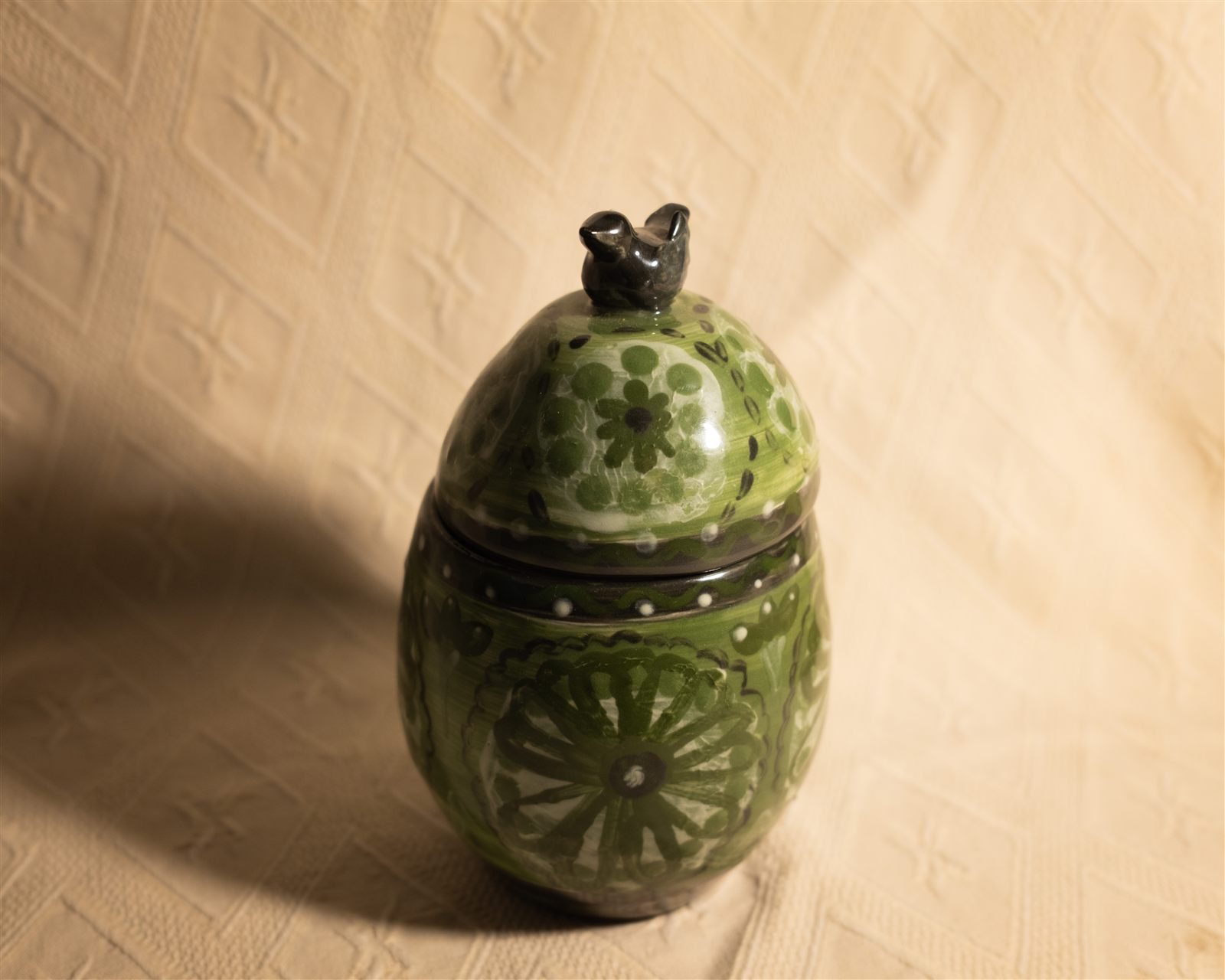 Green floral canister with bird finial, closed